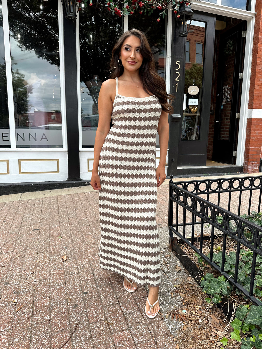 Woman wearing cream and brown stripe knit midi dress with slide slit.