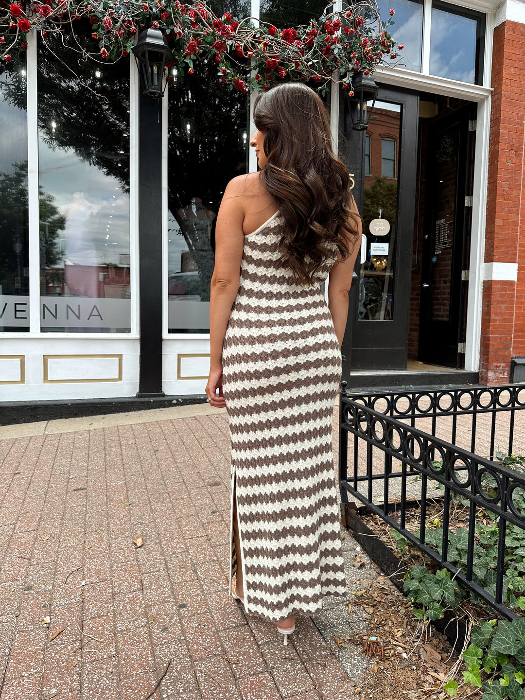 Woman wearing cream and brown stripe knit midi dress with slide slit.