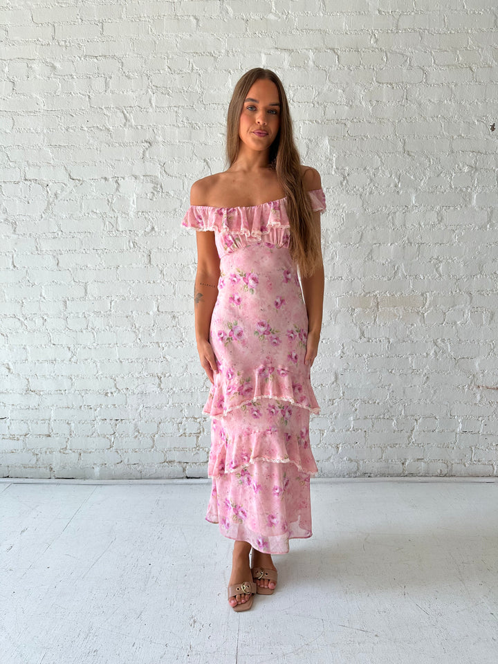 Woman wearing pink floral tiered maxi dress with lace trim detail.