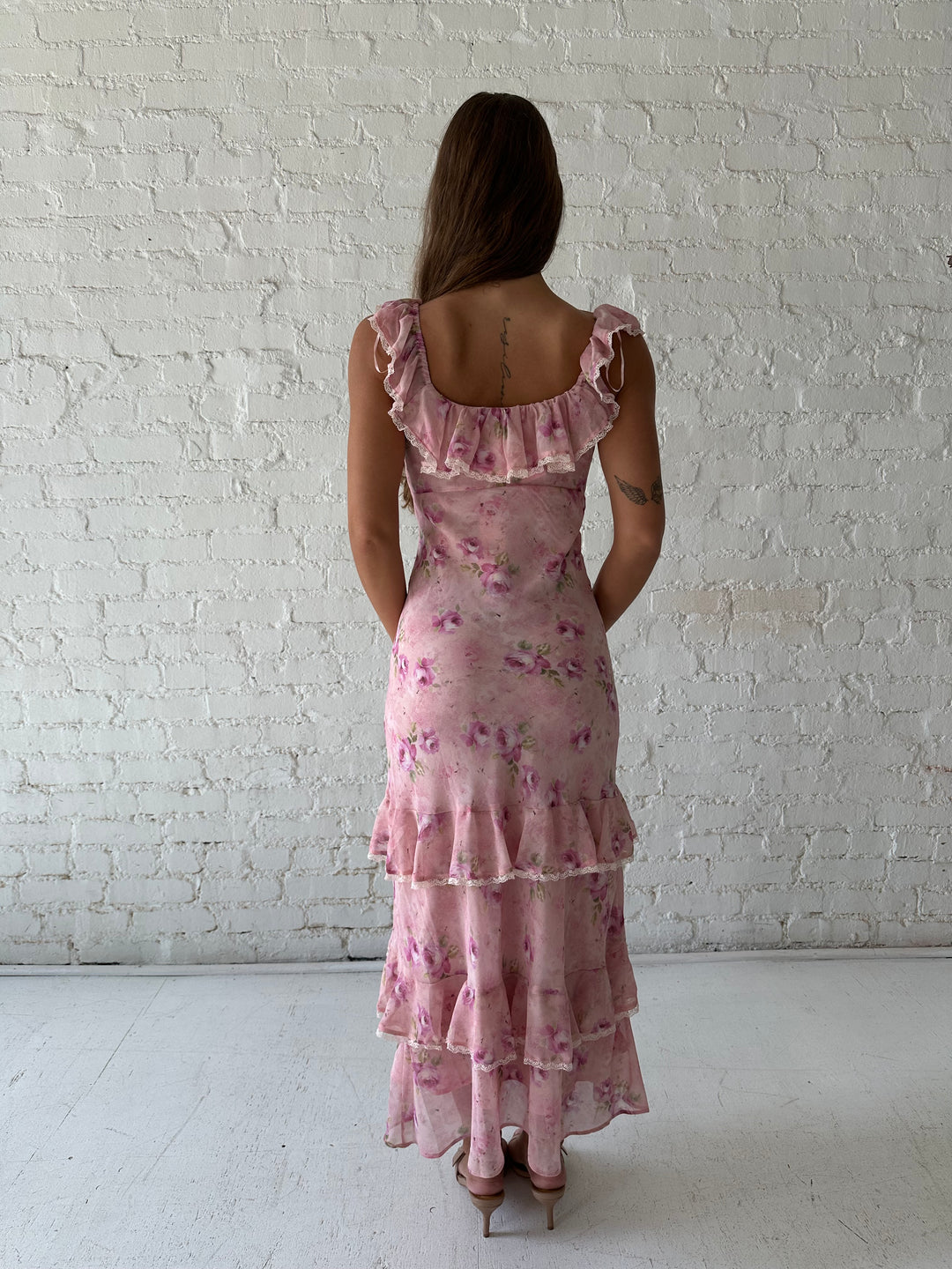 Woman wearing pink floral tiered maxi dress with lace trim detail.