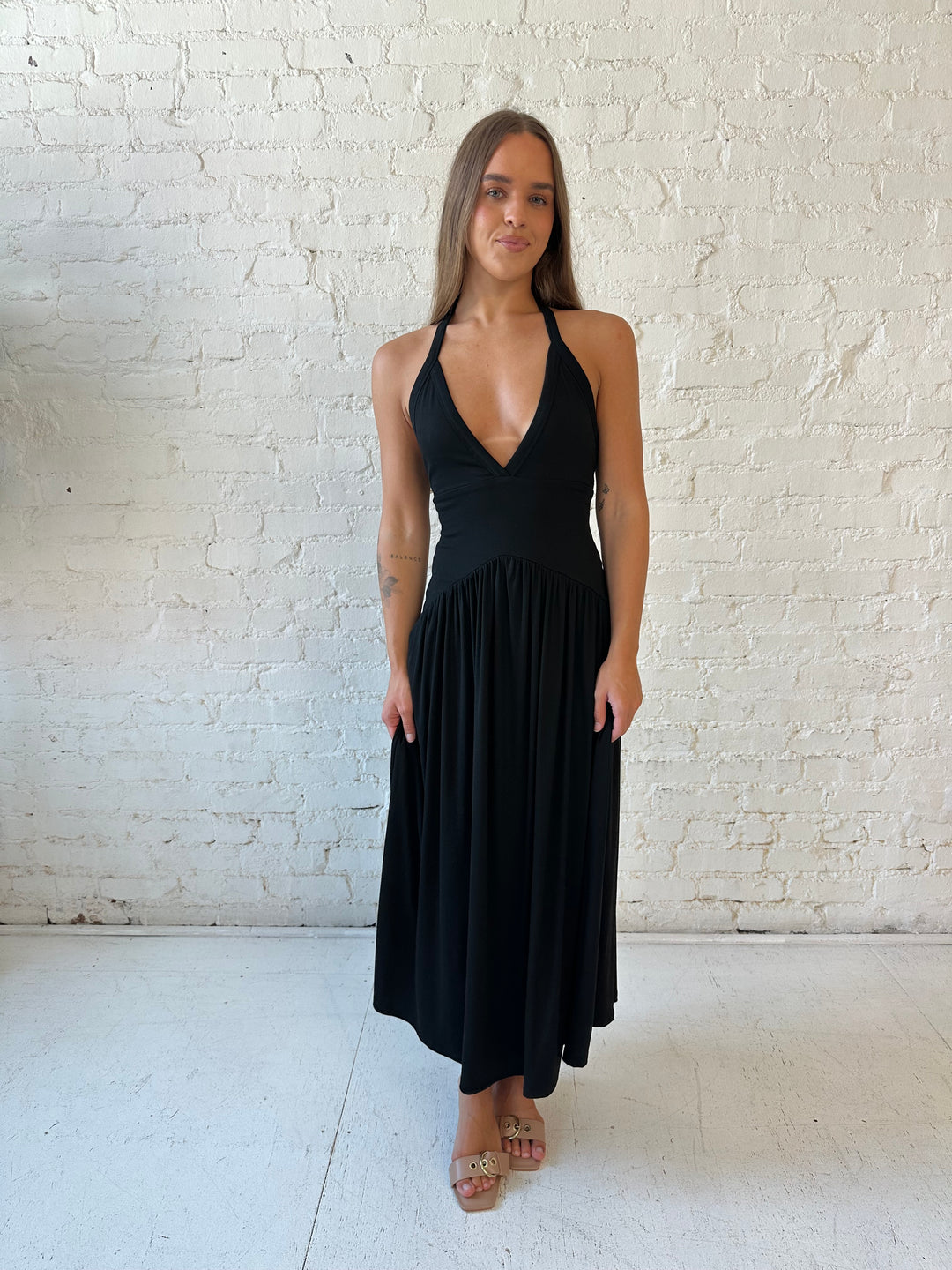 Woman wearing black maxi dress with plunging halter neckline and flowy skirt. 