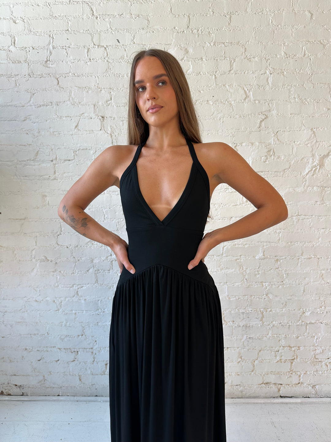 Woman wearing black maxi dress with plunging halter neckline and flowy skirt. 
