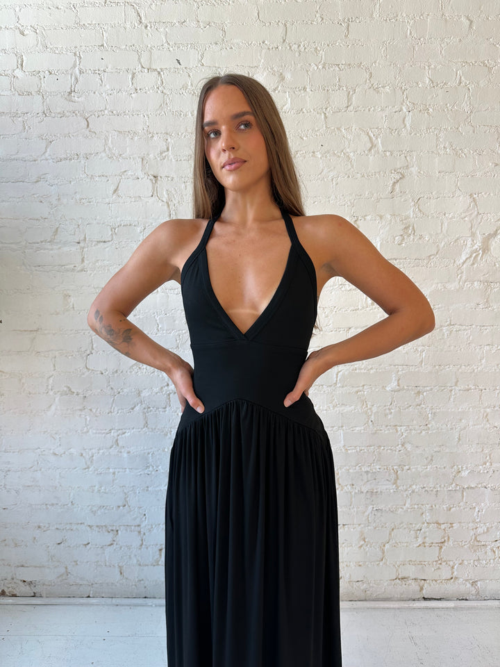 Woman wearing black maxi dress with plunging halter neckline and flowy skirt. 