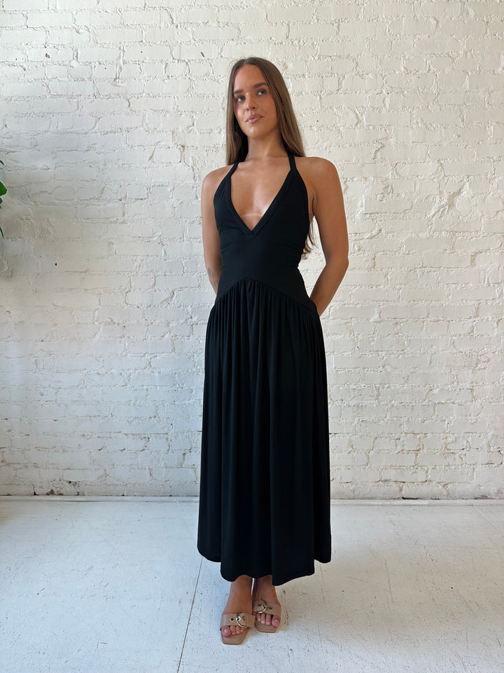 Woman wearing black maxi dress with plunging halter neckline and flowy skirt. 