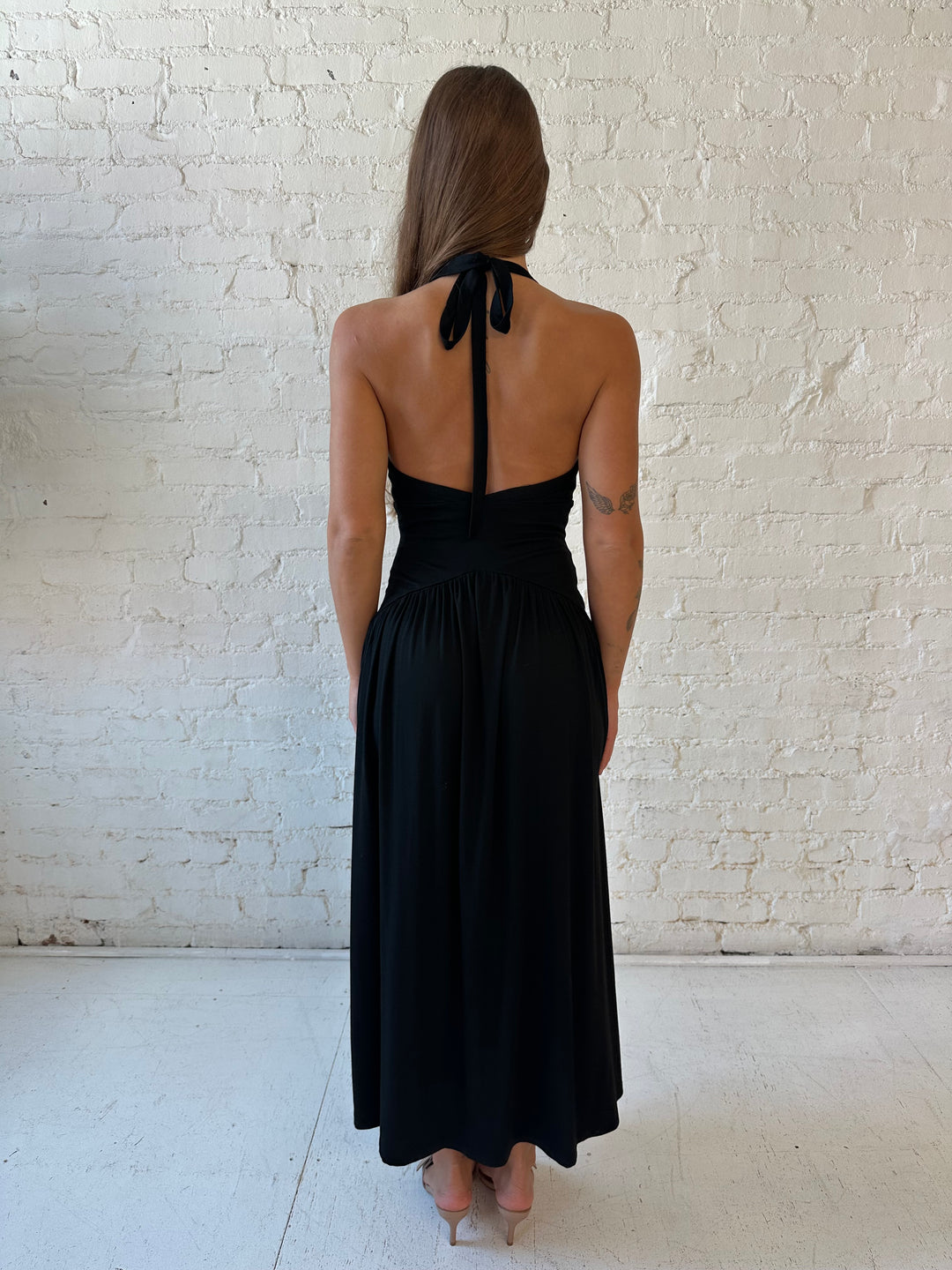Woman wearing black maxi dress with plunging halter neckline and flowy skirt. 