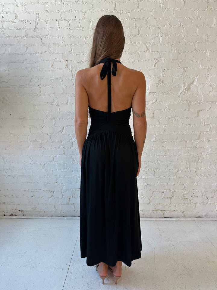 Woman wearing black maxi dress with plunging halter neckline and flowy skirt. 
