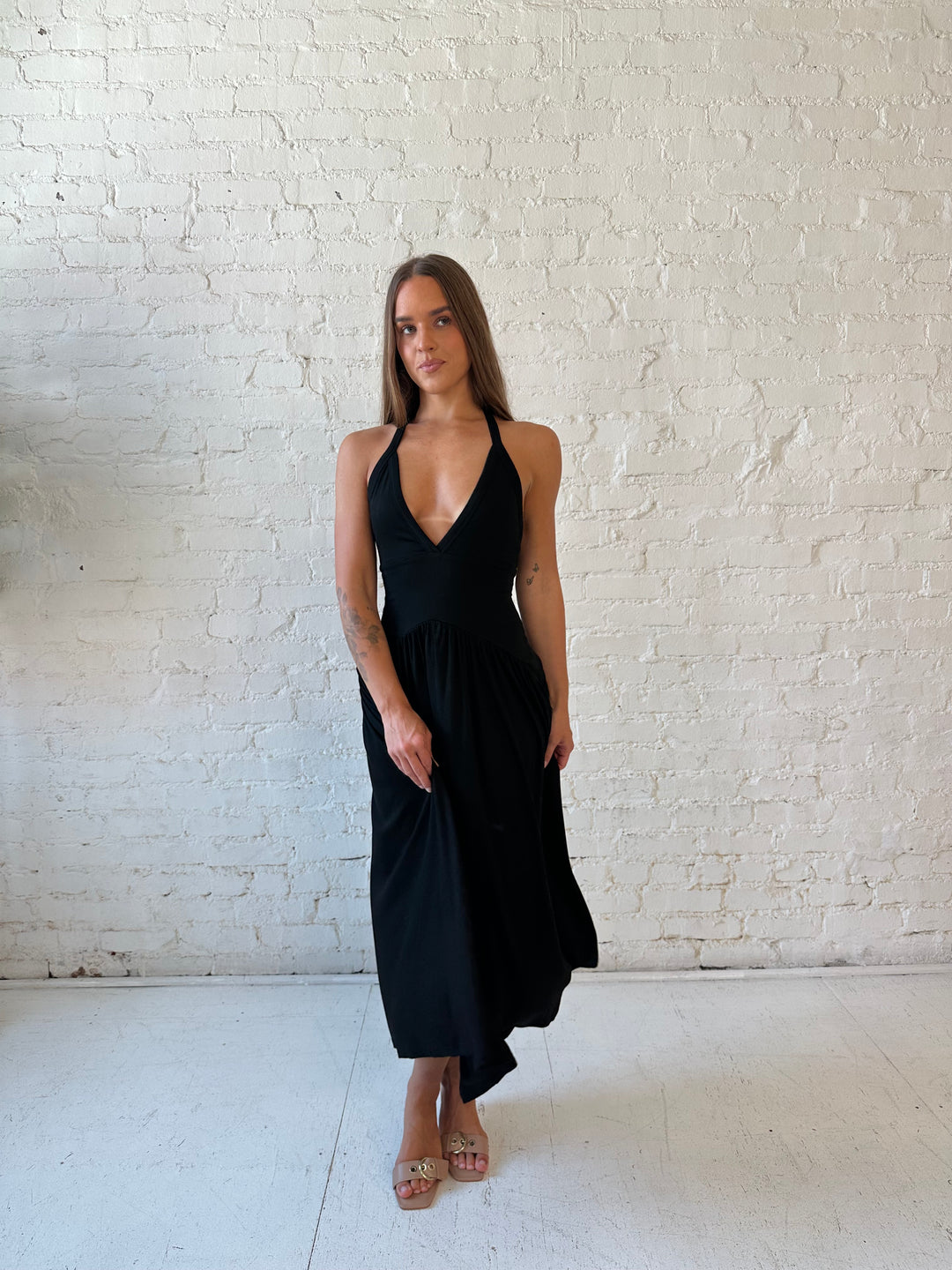 Woman wearing black maxi dress with plunging halter neckline and flowy skirt. 