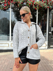 Woman wearing grey chinky oversized button down cardigan with black leather short.
