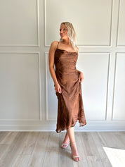 Woman wearing brown floral midi dress with cowl neckline, side slit, and tie back.