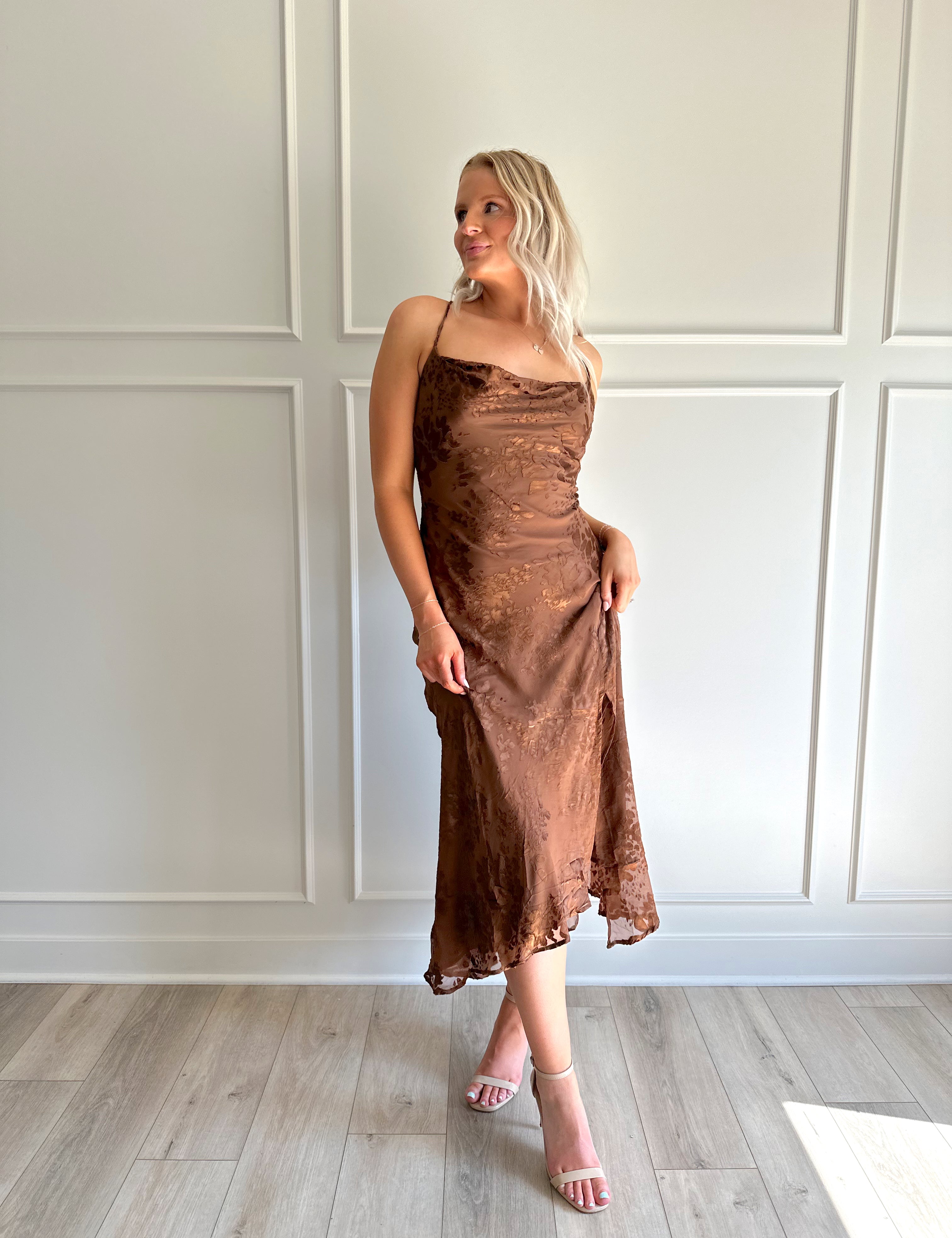 Woman wearing brown floral midi dress with cowl neckline, side slit, and tie back.