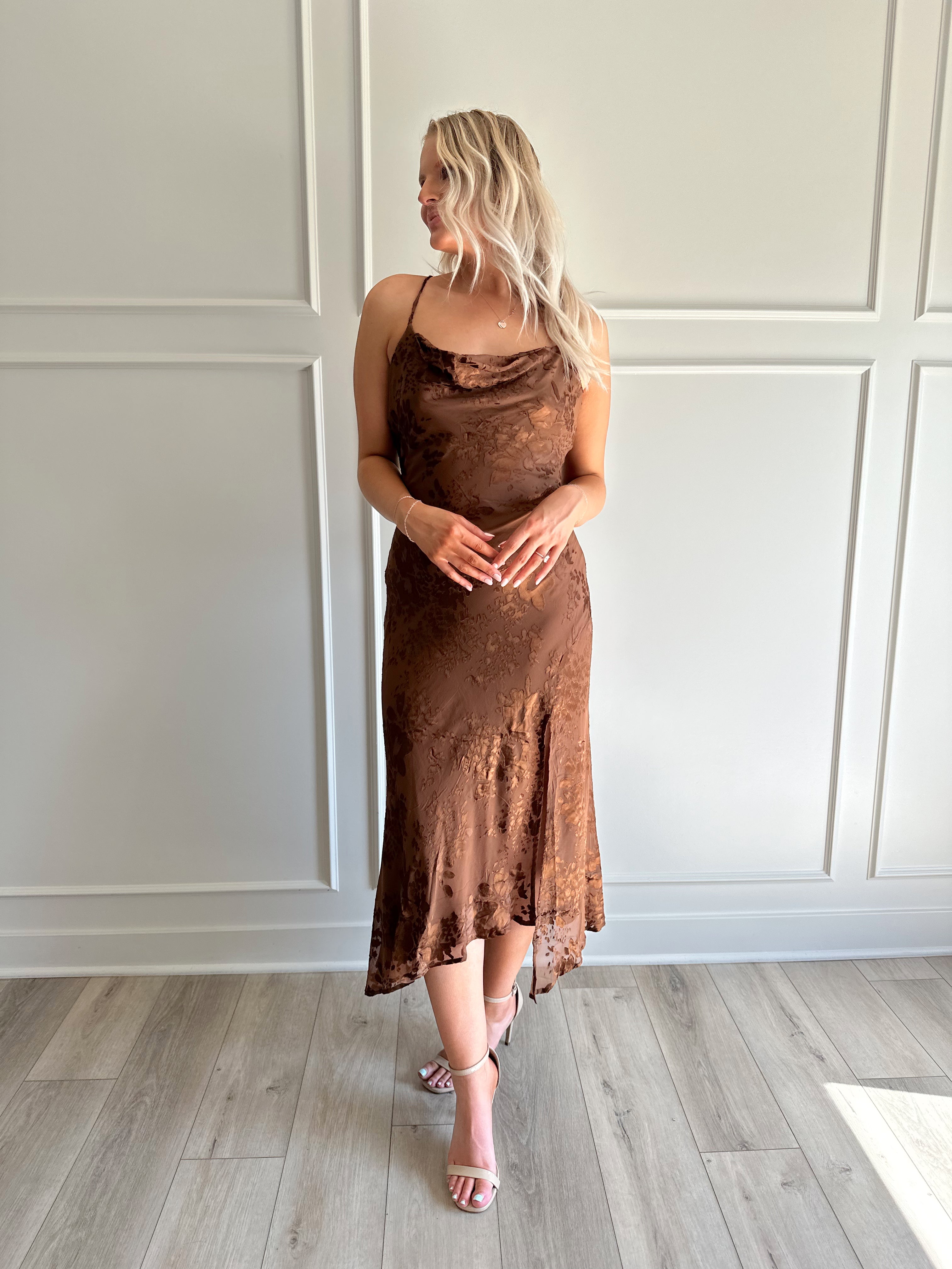 Woman wearing brown floral midi dress with cowl neckline, side slit, and tie back.
