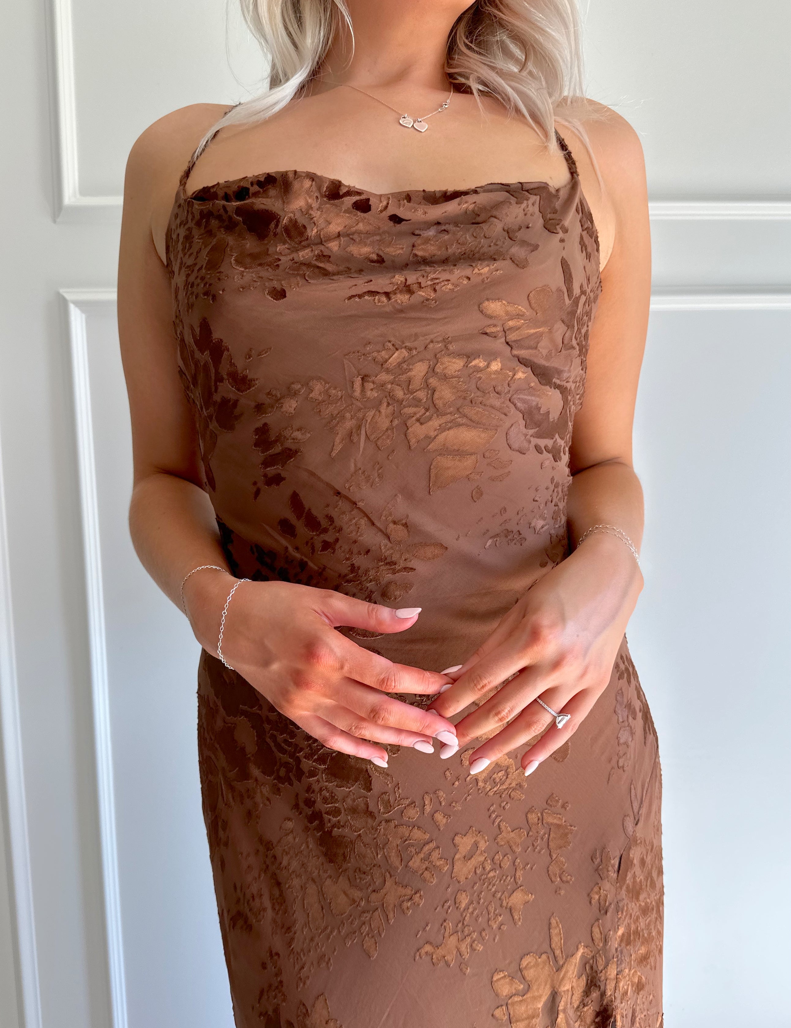 Woman wearing brown floral midi dress with cowl neckline, side slit, and tie back.