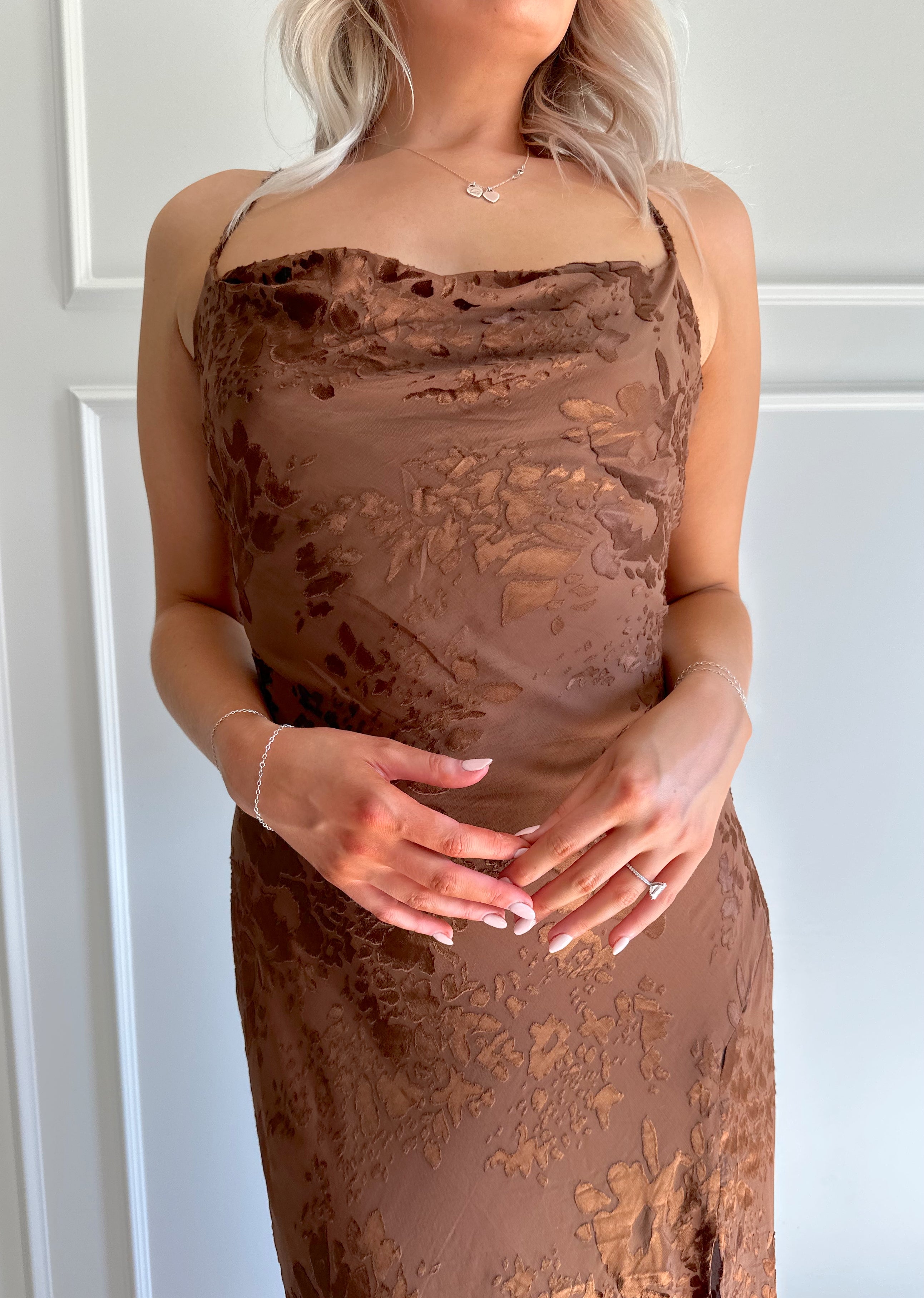 Woman wearing brown floral midi dress with cowl neckline, side slit, and tie back.