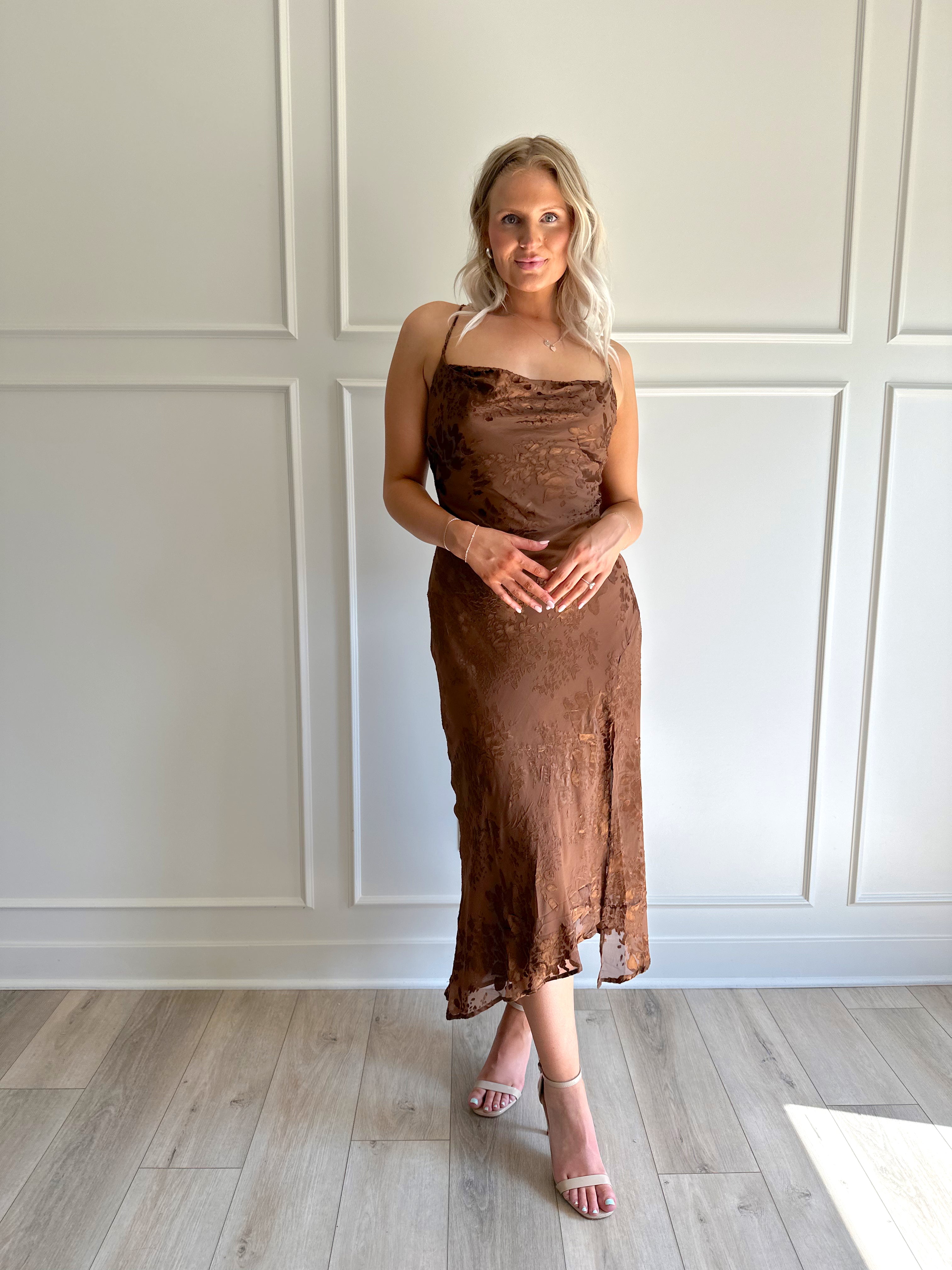 Woman wearing brown floral midi dress with cowl neckline, side slit, and tie back.