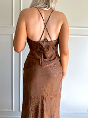 Woman wearing brown floral midi dress with cowl neckline, side slit, and tie back.