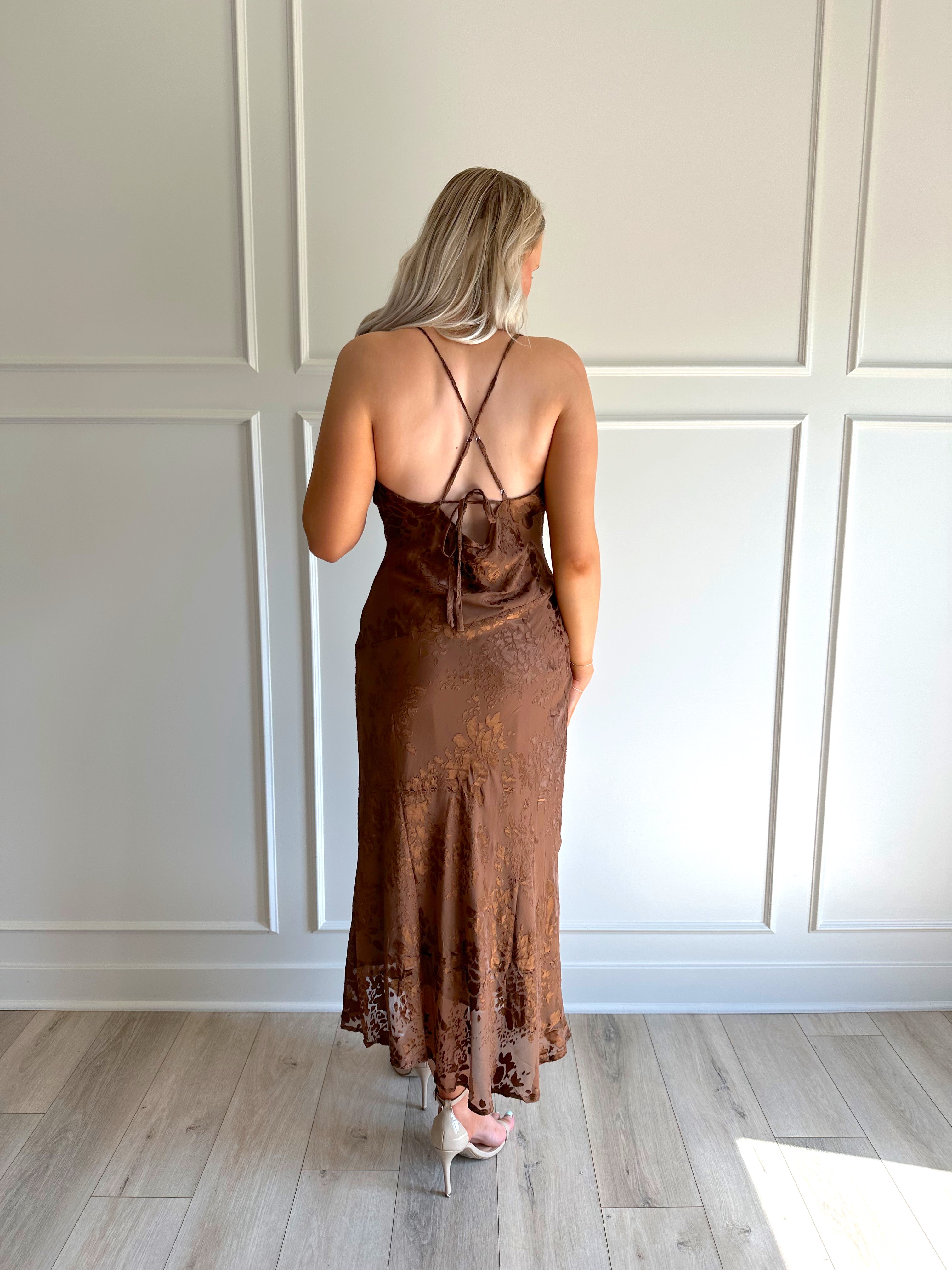 Woman wearing brown floral midi dress with cowl neckline, side slit, and tie back.