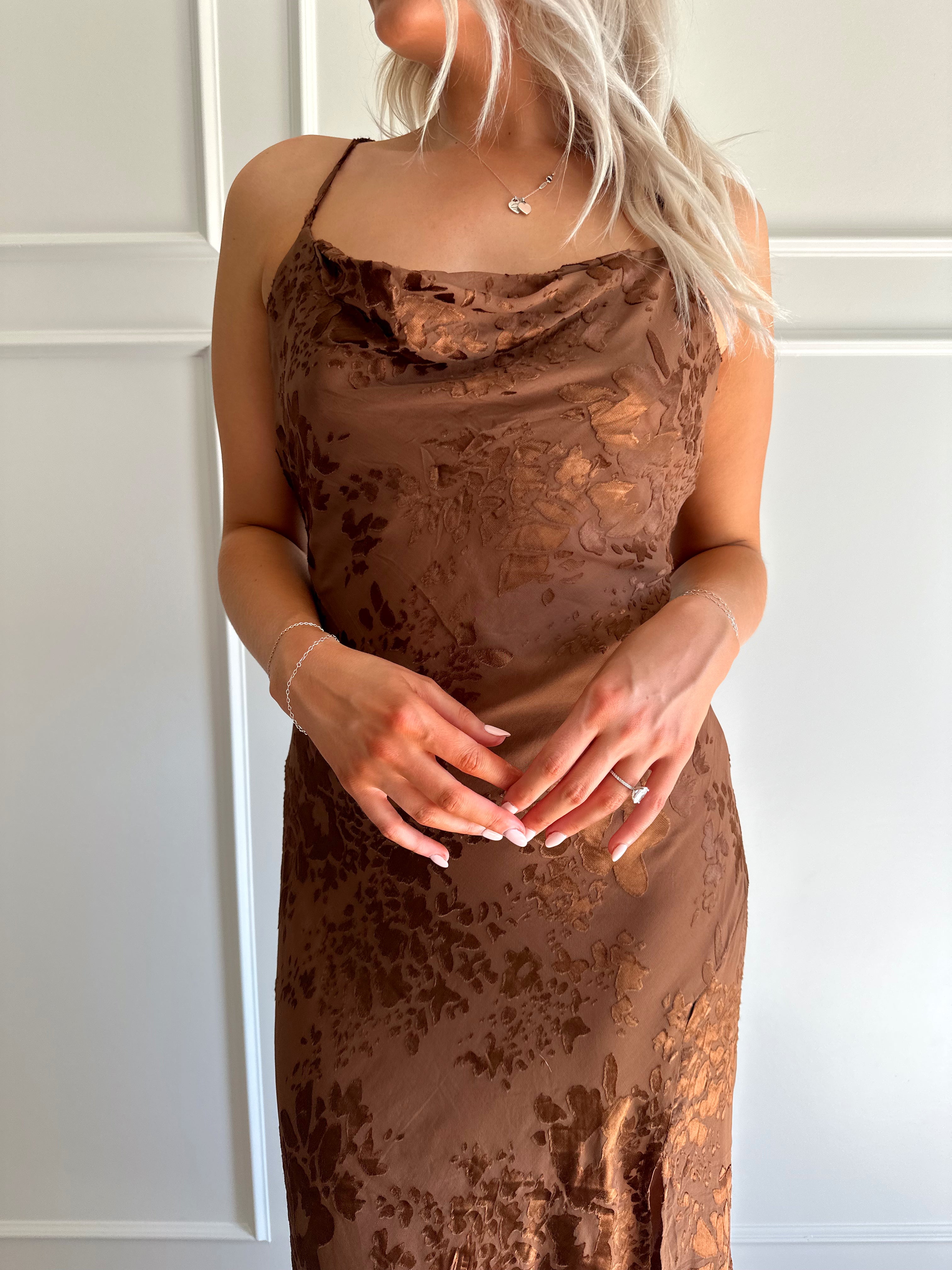 Woman wearing brown floral midi dress with cowl neckline, side slit, and tie back.
