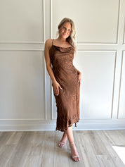 Woman wearing brown floral midi dress with cowl neckline, side slit, and tie back.