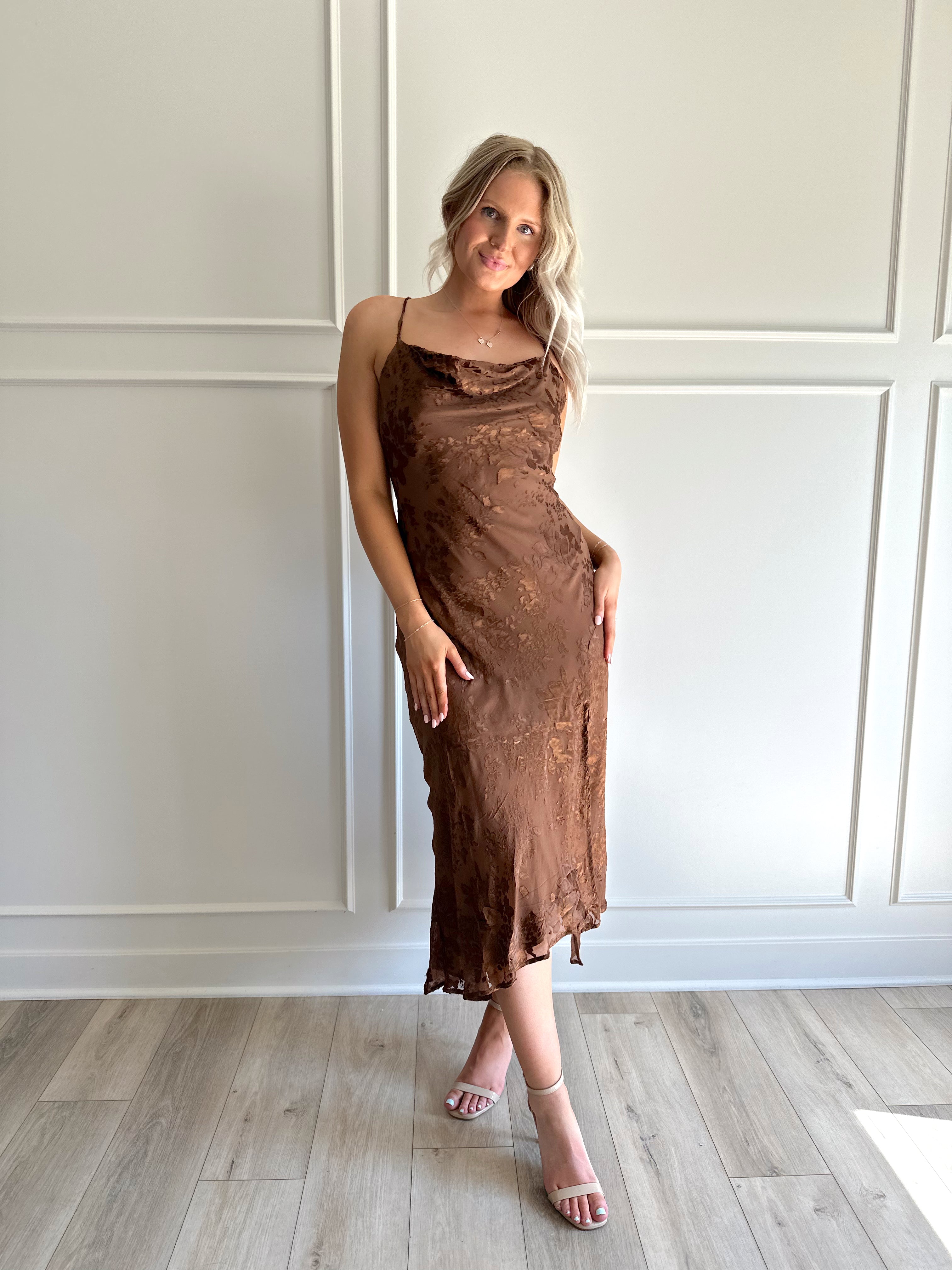 Woman wearing brown floral midi dress with cowl neckline, side slit, and tie back.