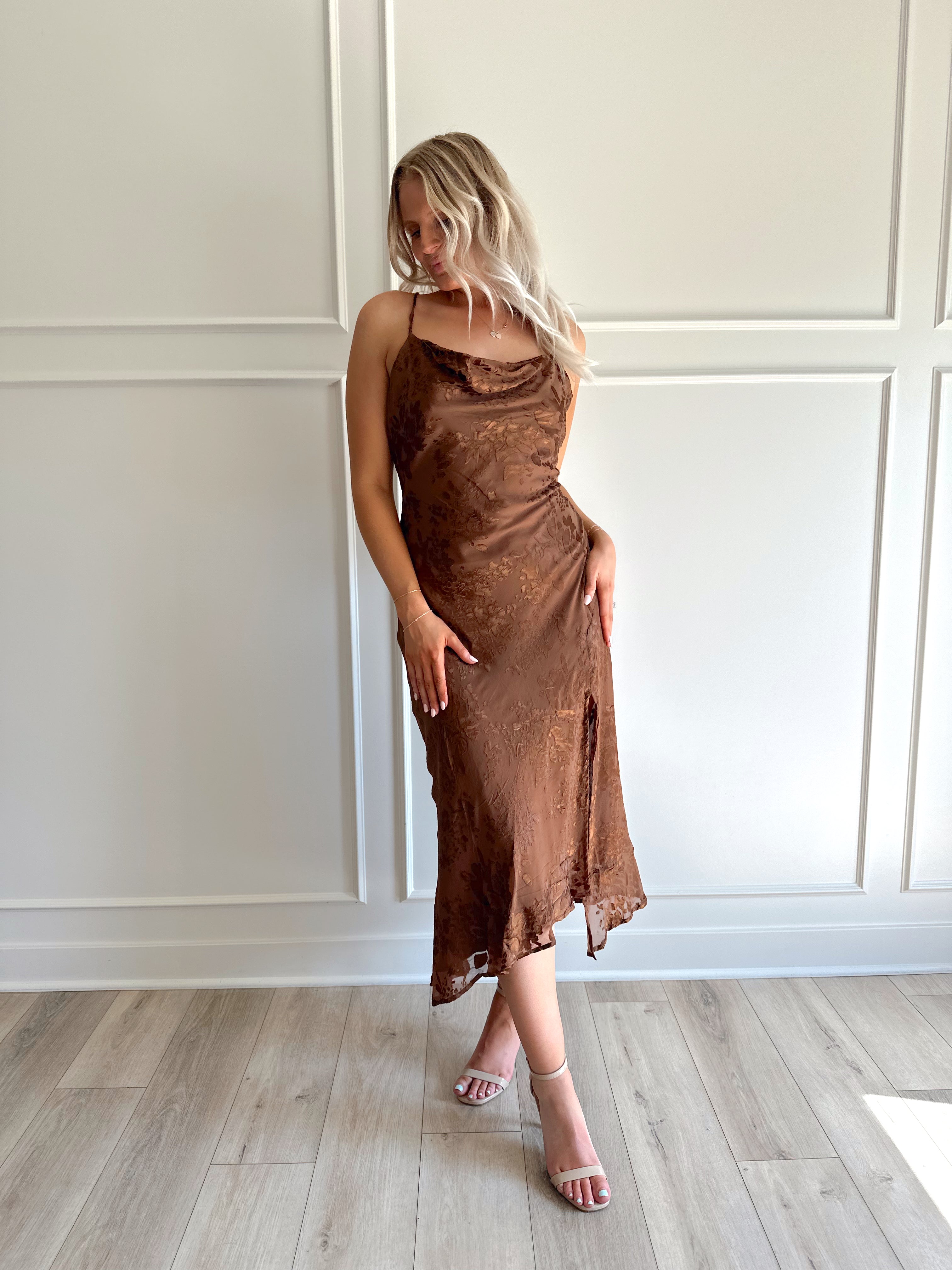 Woman wearing brown floral midi dress with cowl neckline, side slit, and tie back.