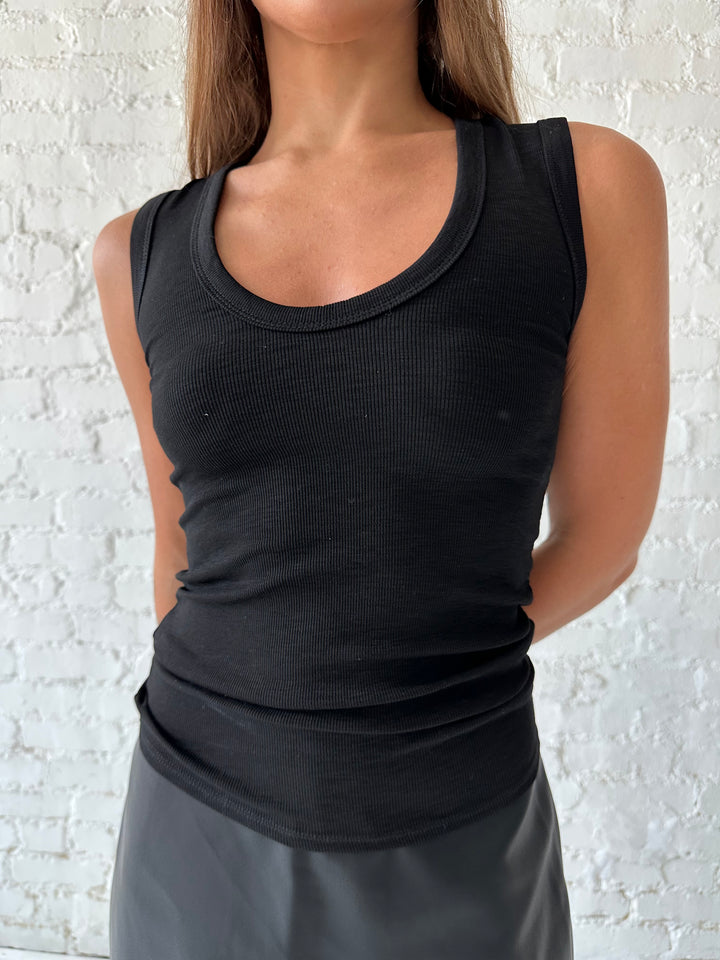 Woman wearing black scoop neck tank top with black leather mini skort. 