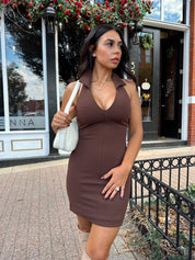 Woman wearing brown mini dress with front zipper closure, and collar neckline detail. 
