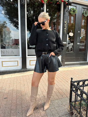Woman wearing black knit button down cardigan and black leather short. 