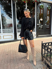 Woman wearing black knit button down cardigan and black leather short. 