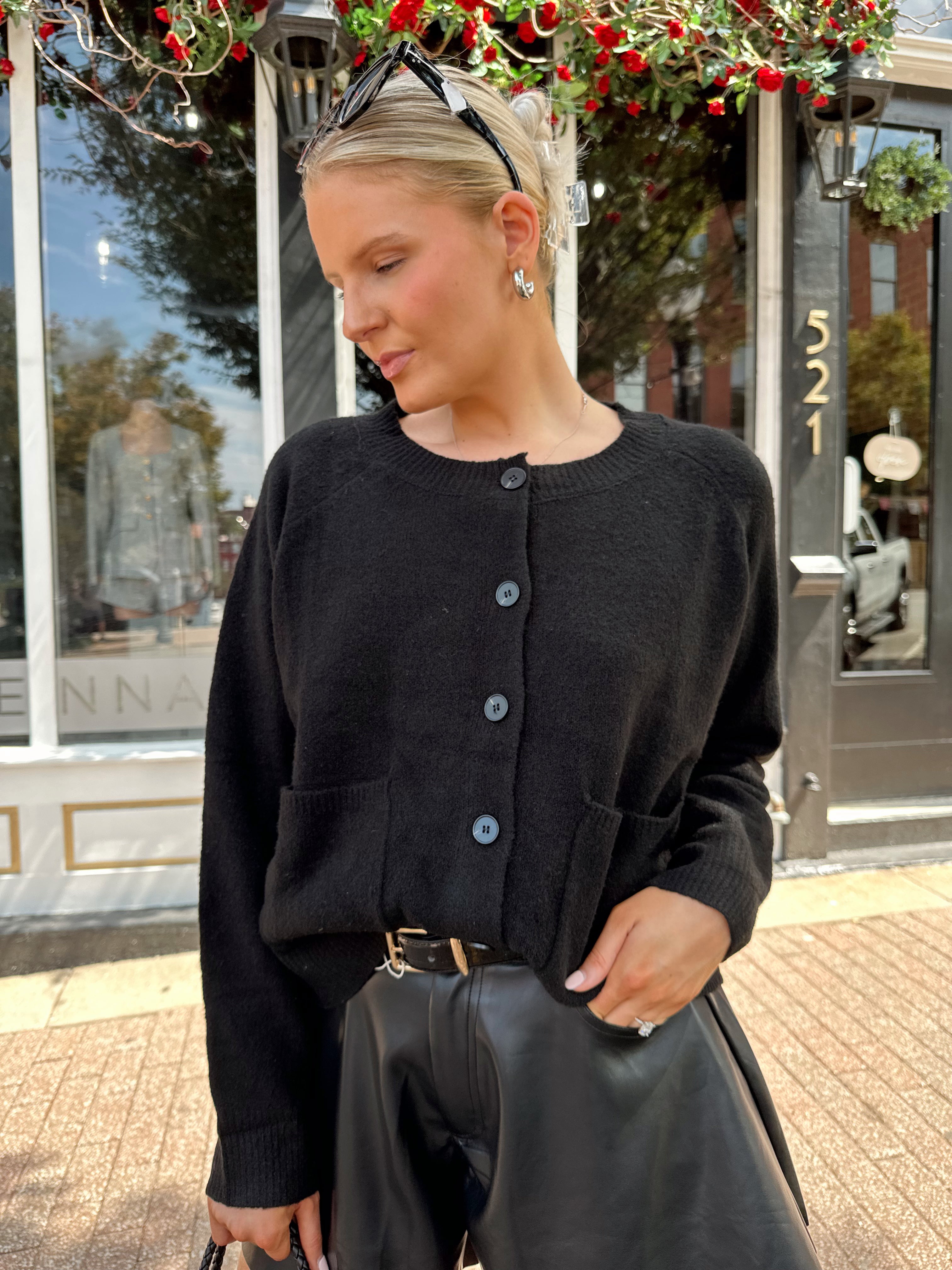 Woman wearing black knit button down cardigan and black leather short. 