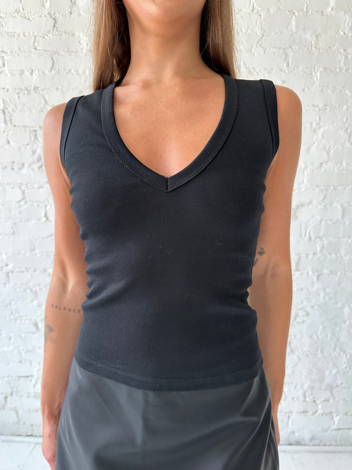 Woman wearing black fitted tank top with v-neckline, and a black leather mini skort. 