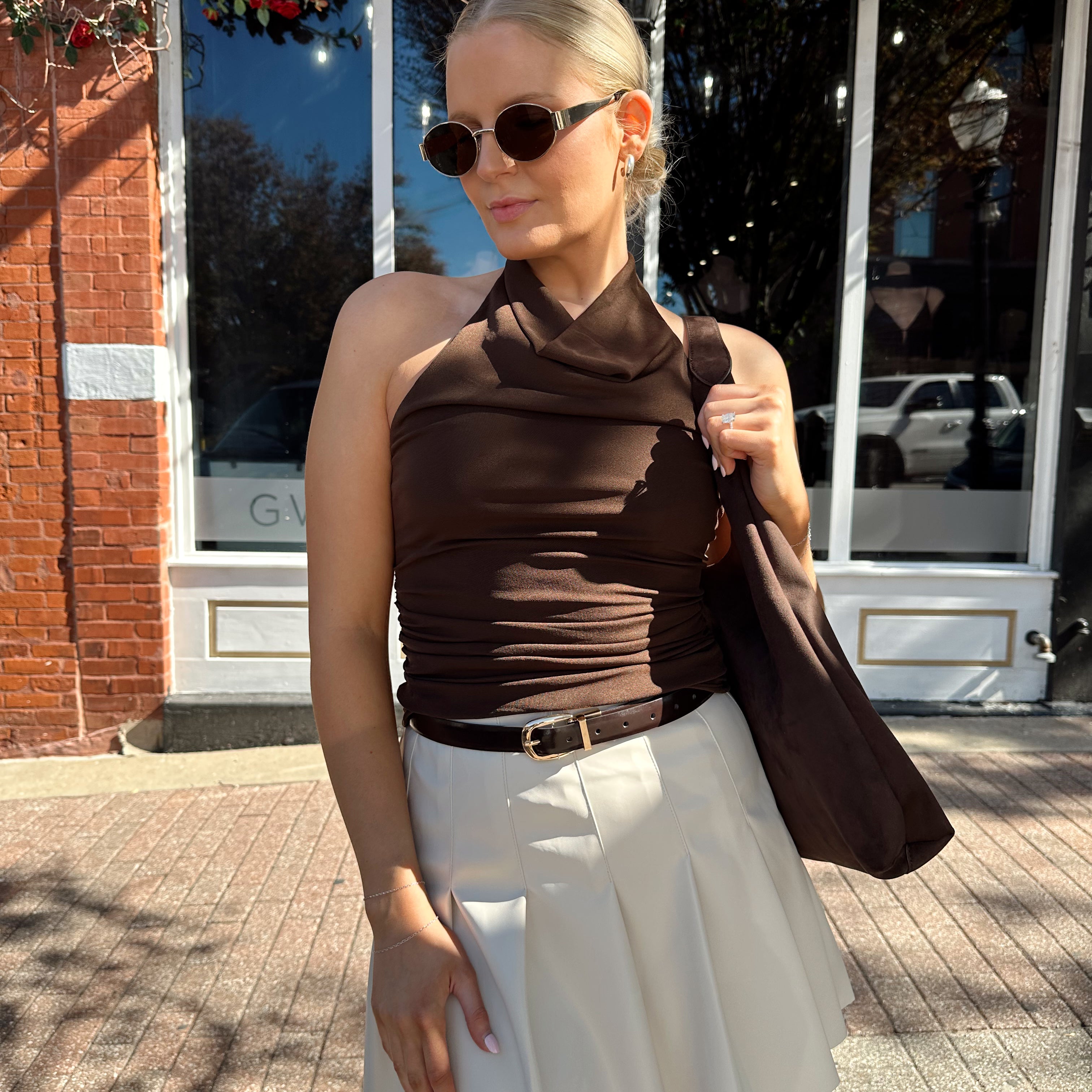 Woman wearing brown mesh, cowl, halter neck top.