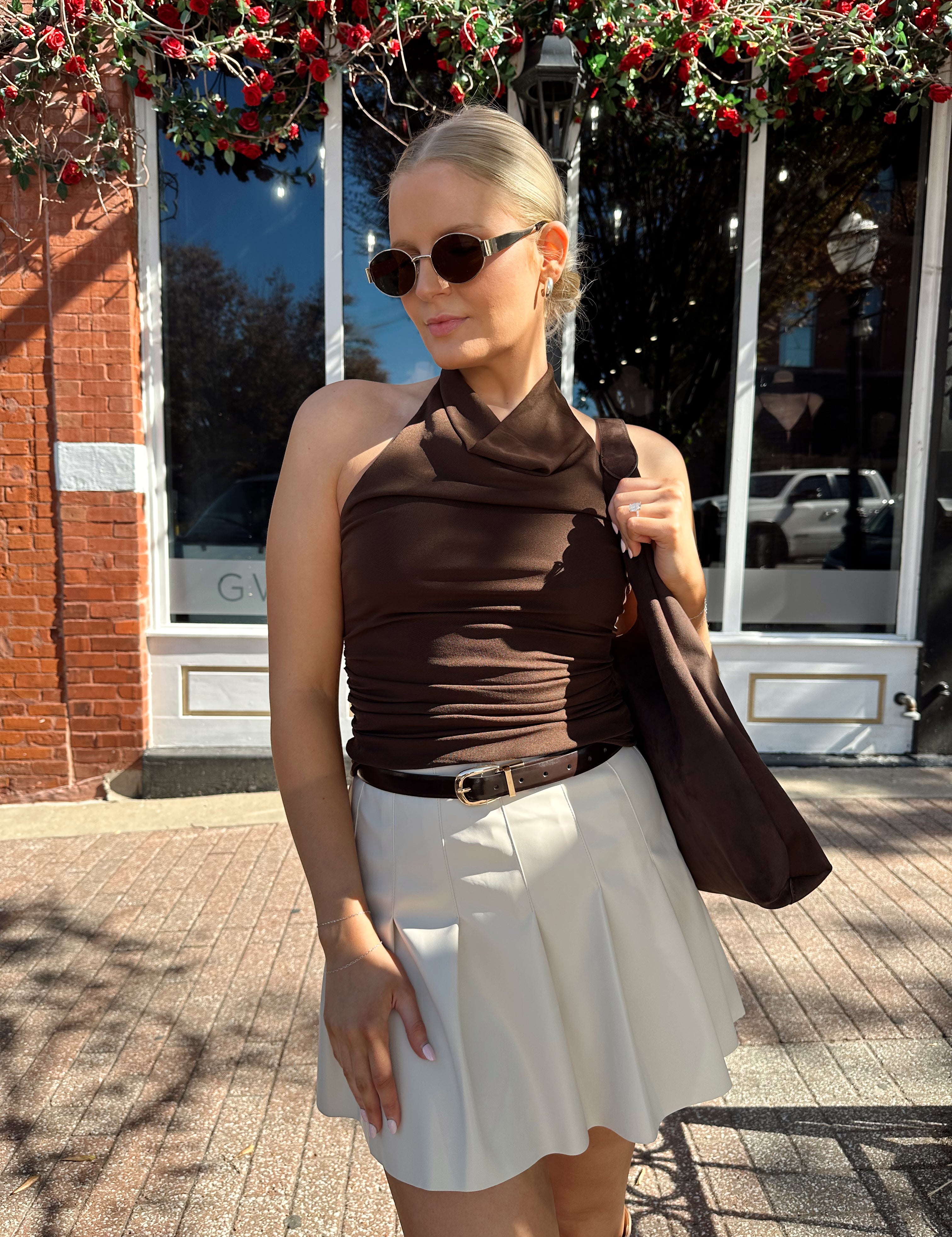 Woman wearing brown mesh, cowl, halter neck top.