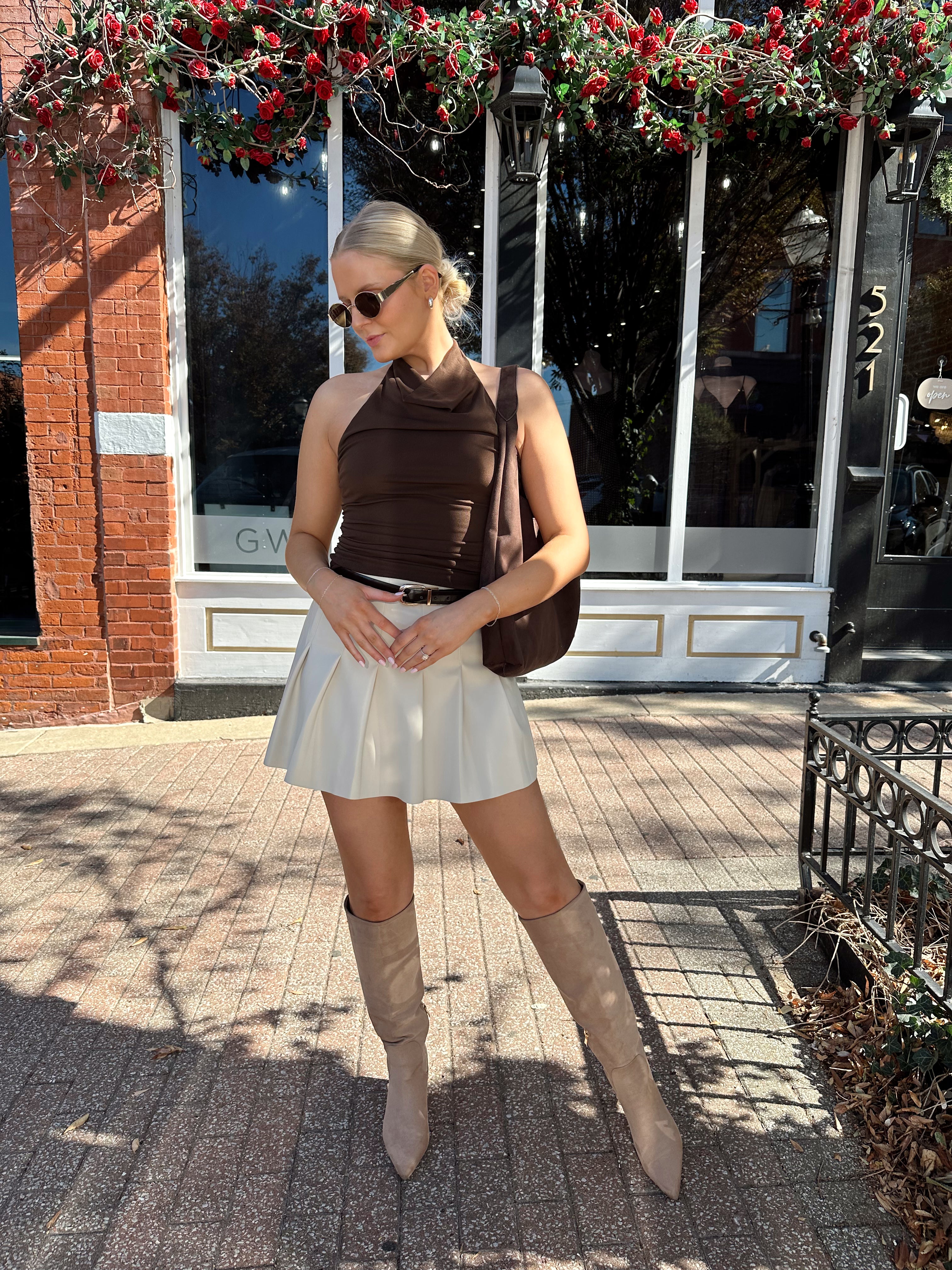 Woman wearing brown mesh, cowl, halter neck top.