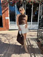 Woman wearing brown mesh, cowl, halter neck top.