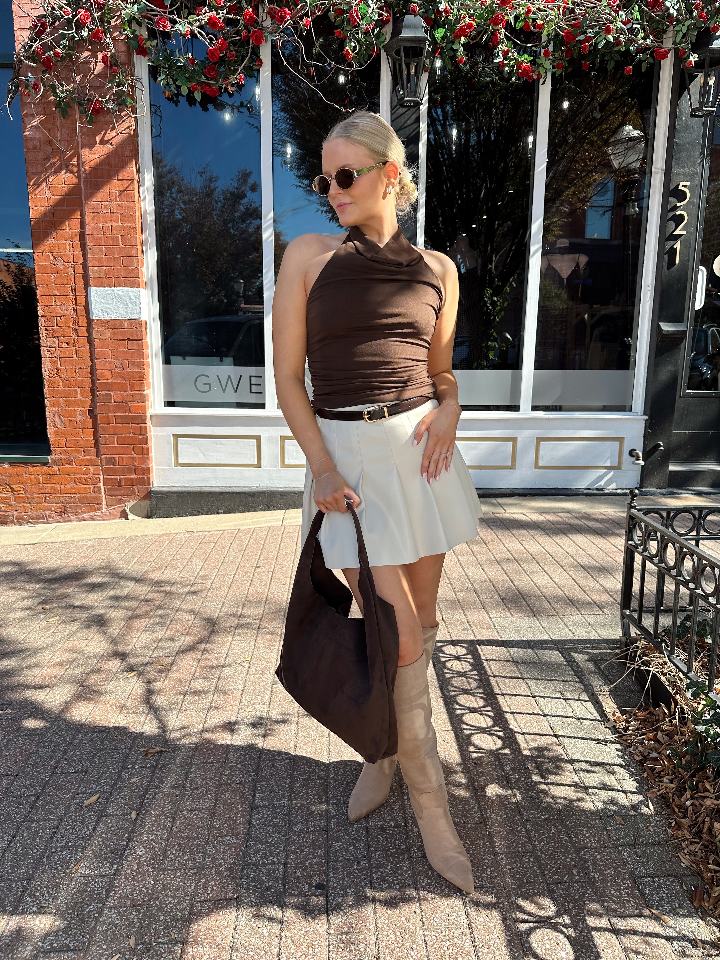 Woman wearing brown mesh, cowl, halter neck top.