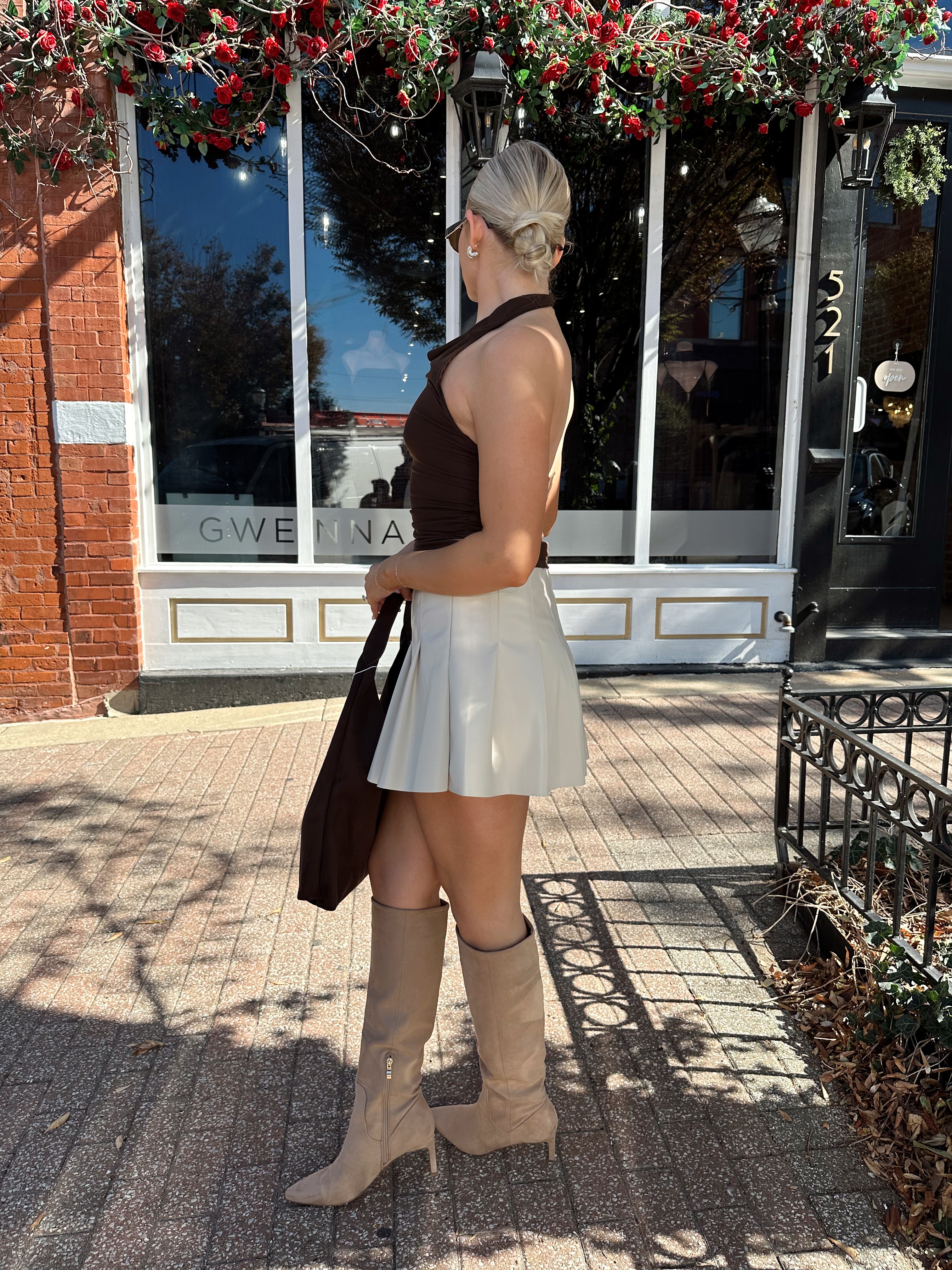 Woman wearing brown mesh, cowl, halter neck top.