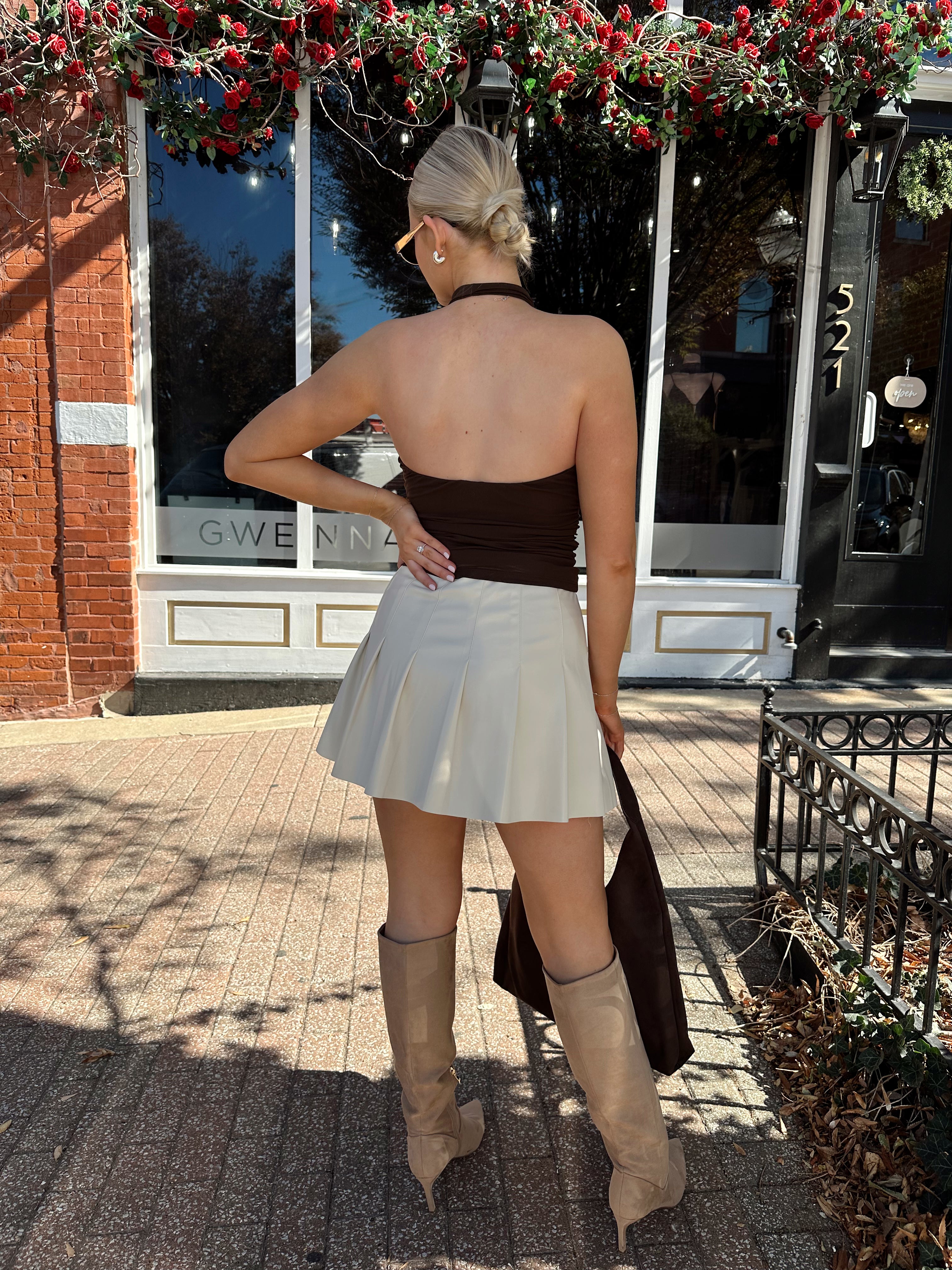 Woman wearing brown mesh, cowl, halter neck top.