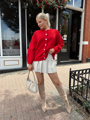 Red oversized button down cardigan with cream leather pleated mini skirt. 