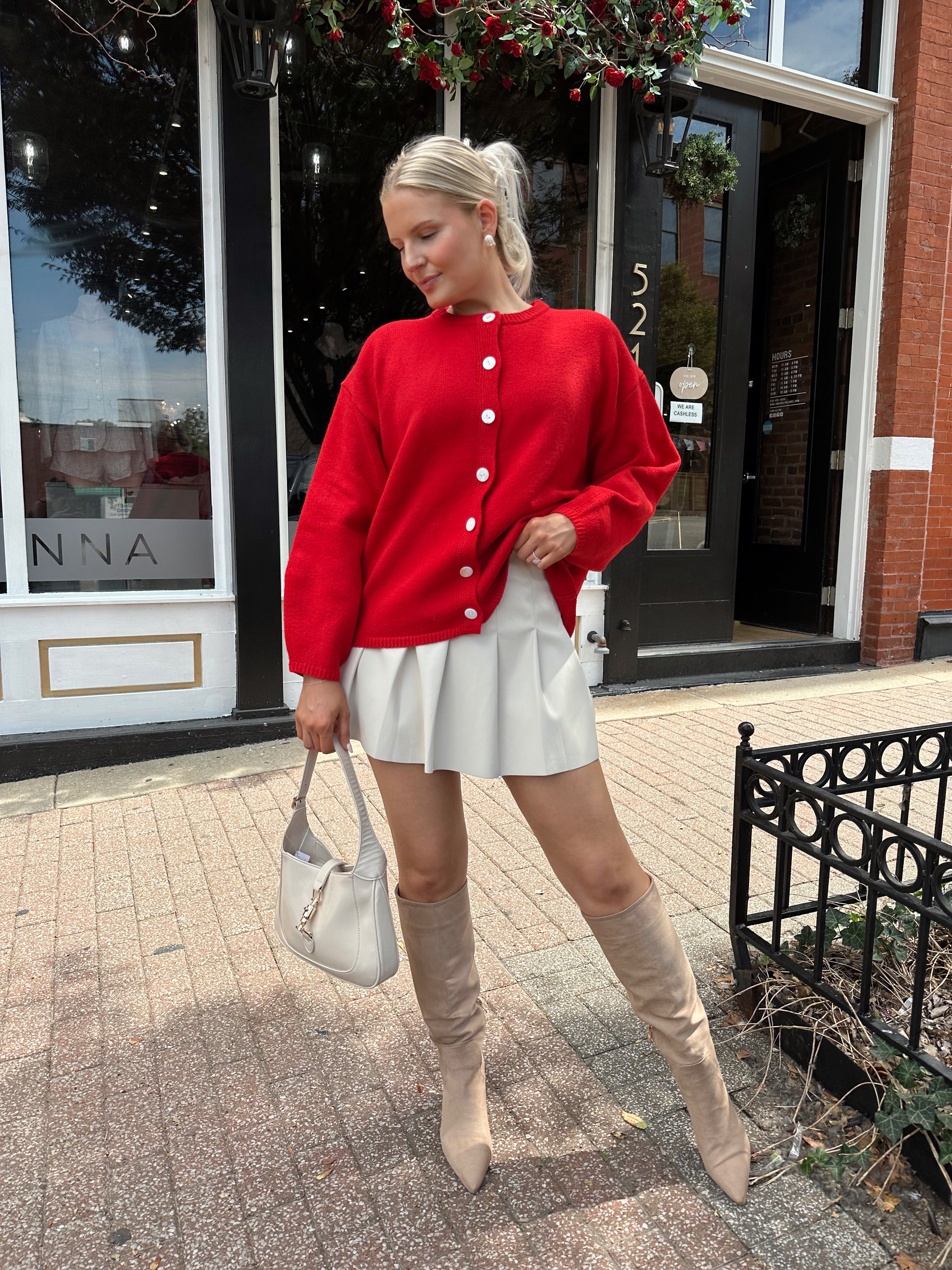 Red oversized button down cardigan with cream leather pleated mini skirt. 
