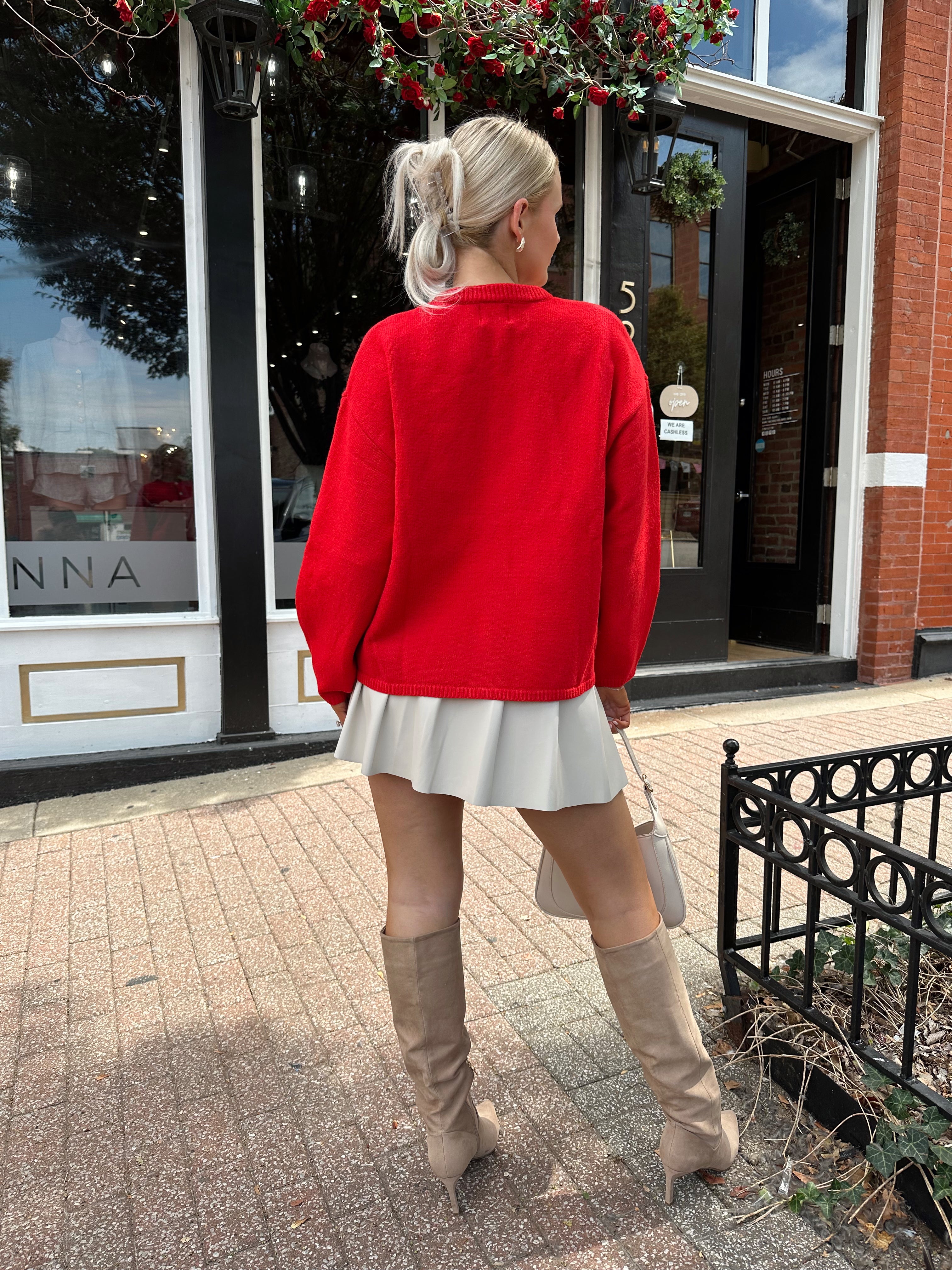 Red oversized button down cardigan with cream leather pleated mini skirt. 