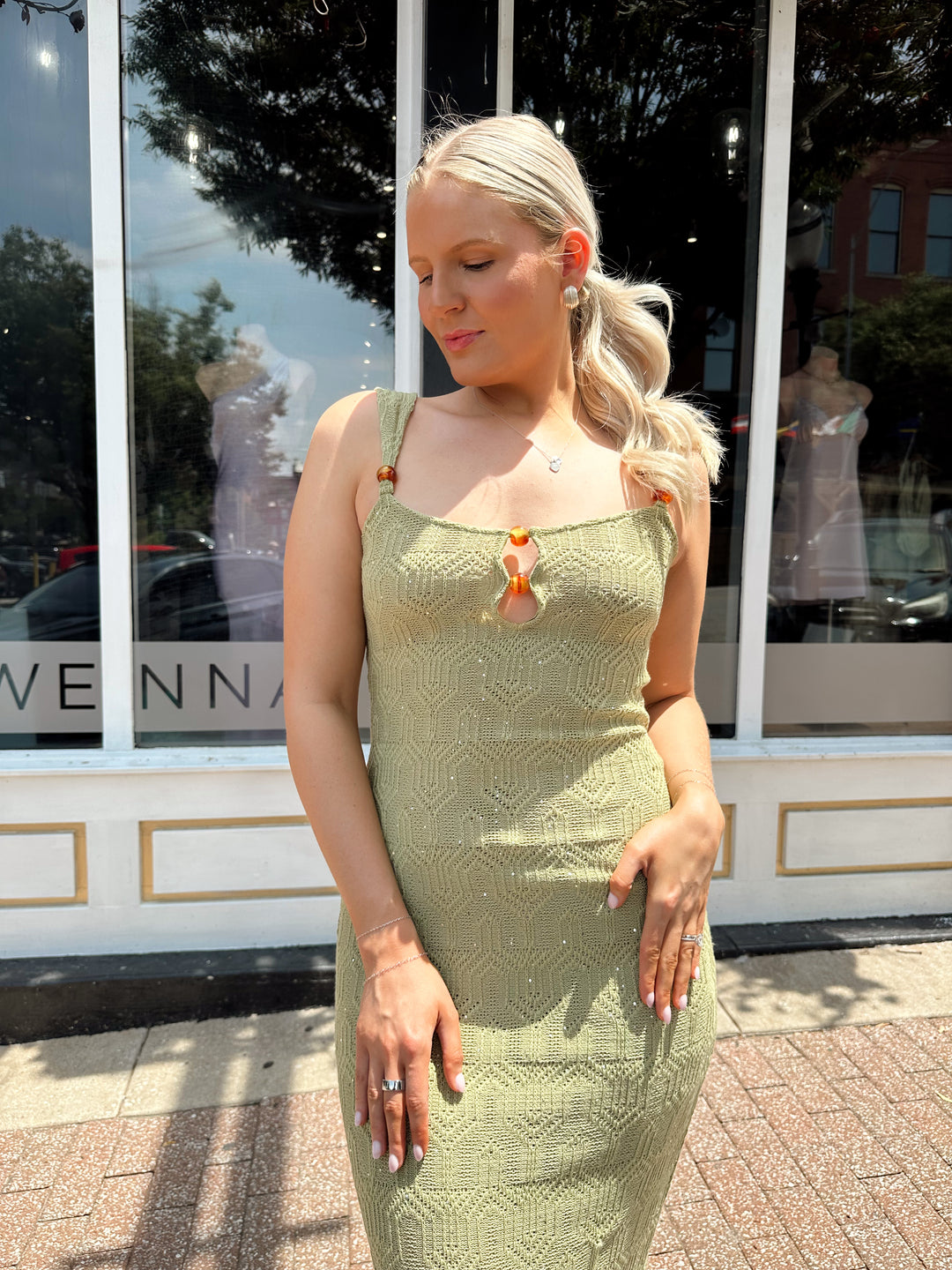 Woman wearing olive green knit maxi dress with subtle sequin shimmer and beaded detailing. 