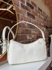 Bone leather shoulder bag with zip closure, sleek silhouette, and adjustable strap