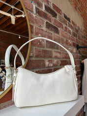 Bone leather shoulder bag with zip closure, sleek silhouette, and adjustable strap