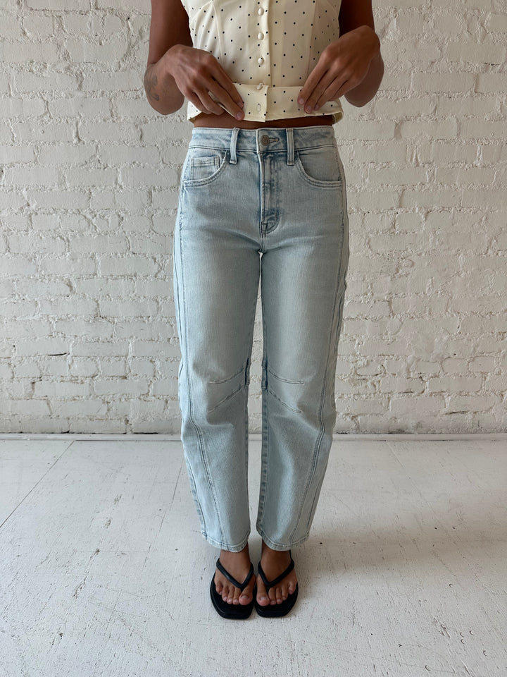 Woman wearing light wash barrel jean with front seam detail and polka dot halter top.