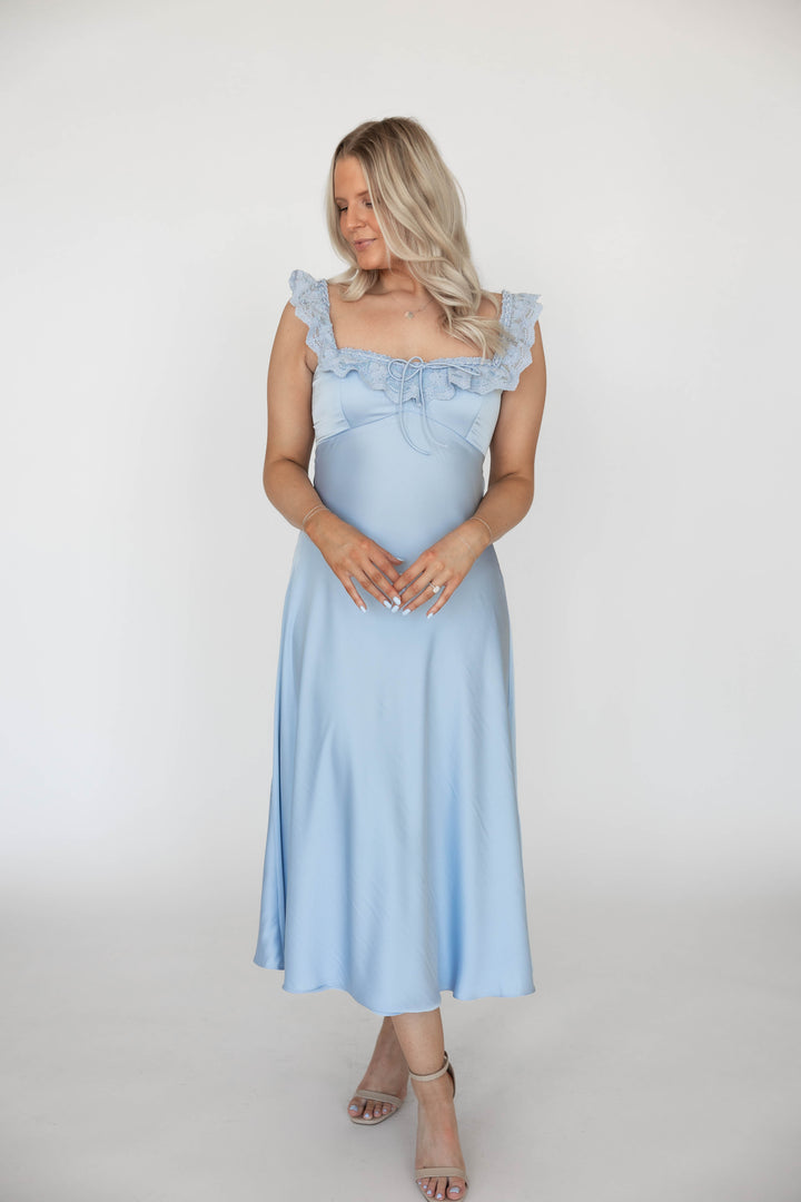 Woman wearing light blue satin midi dress with lace trim detailing. 