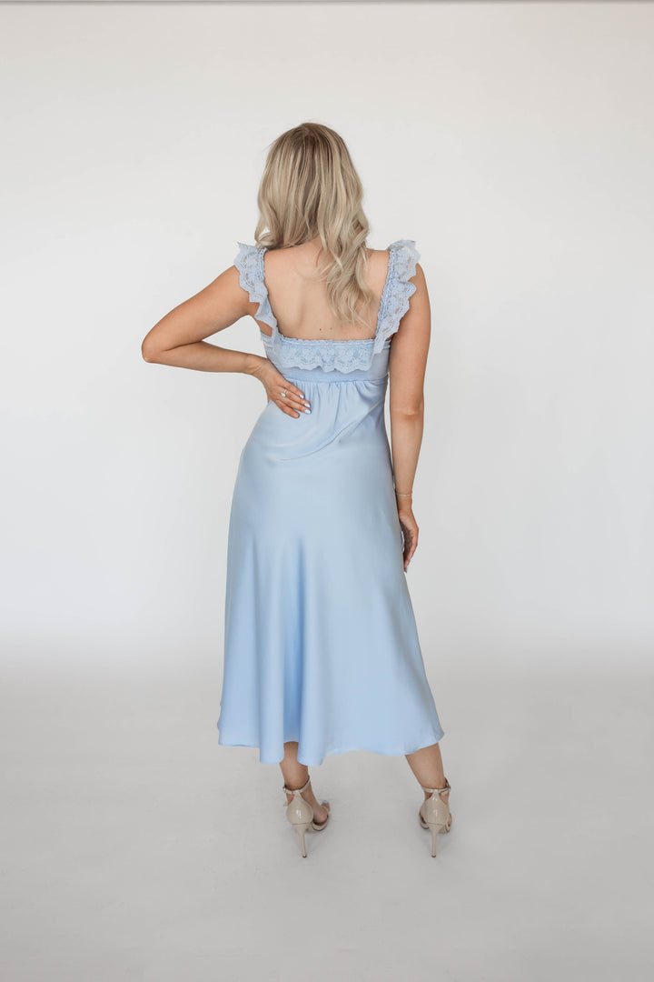 Woman wearing light blue satin midi dress with lace trim detailing. 