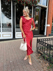 Woman wearing red cowl neck satin midi dress with polka dot pattern. 