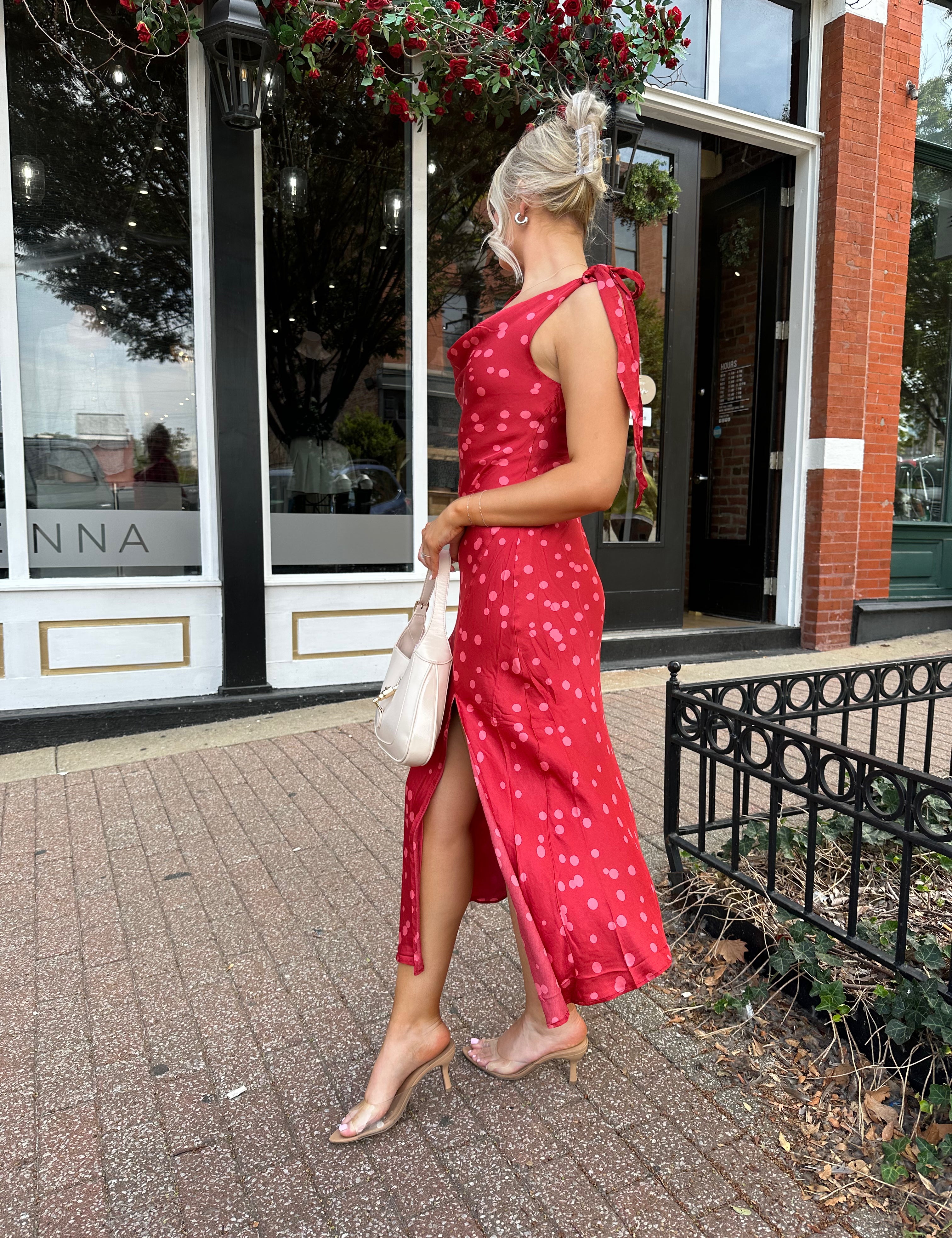 Woman wearing red cowl neck satin midi dress with polka dot pattern. 