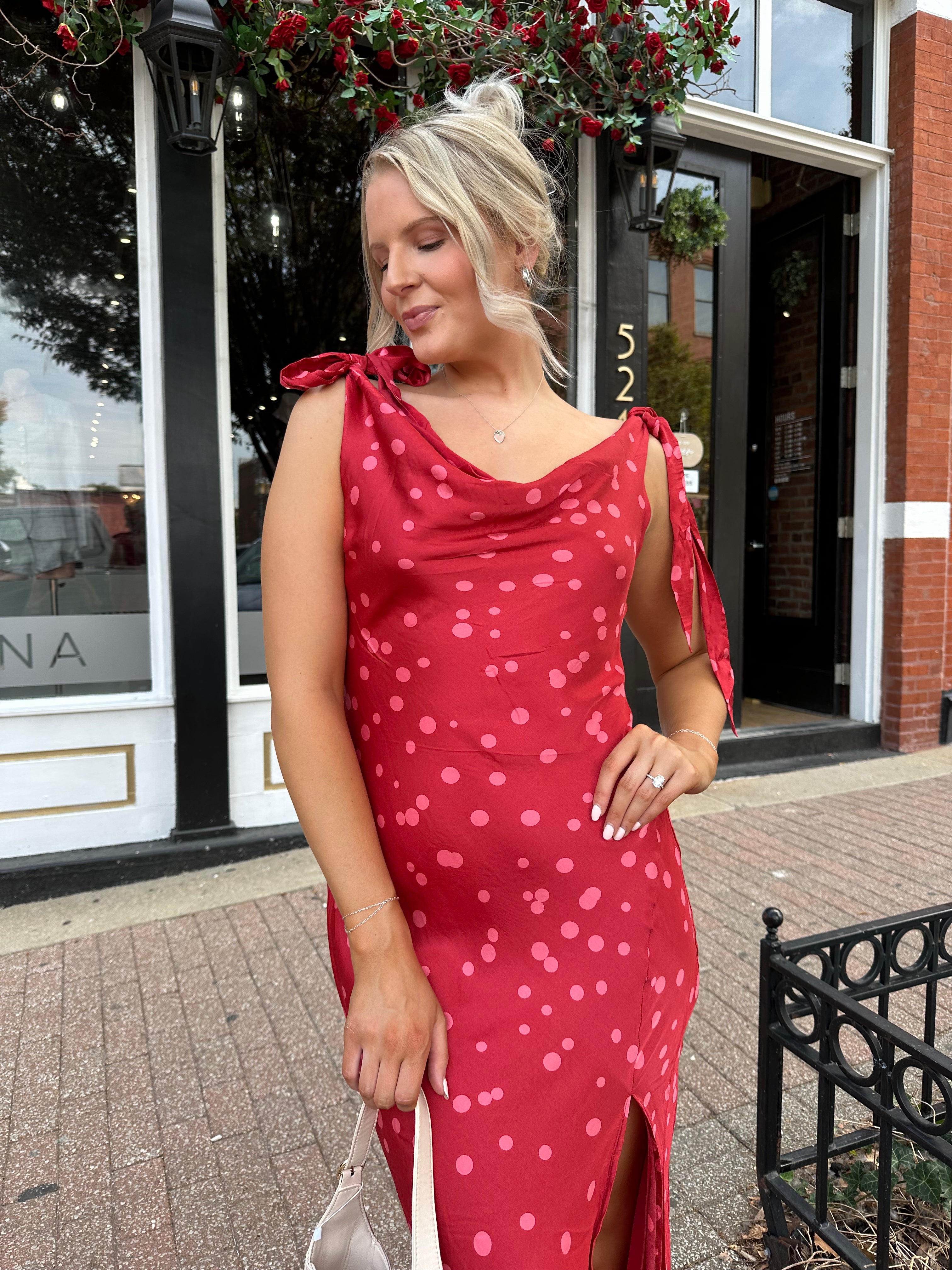 Woman wearing red cowl neck satin midi dress with polka dot pattern. 