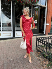 Woman wearing red cowl neck satin midi dress with polka dot pattern. 